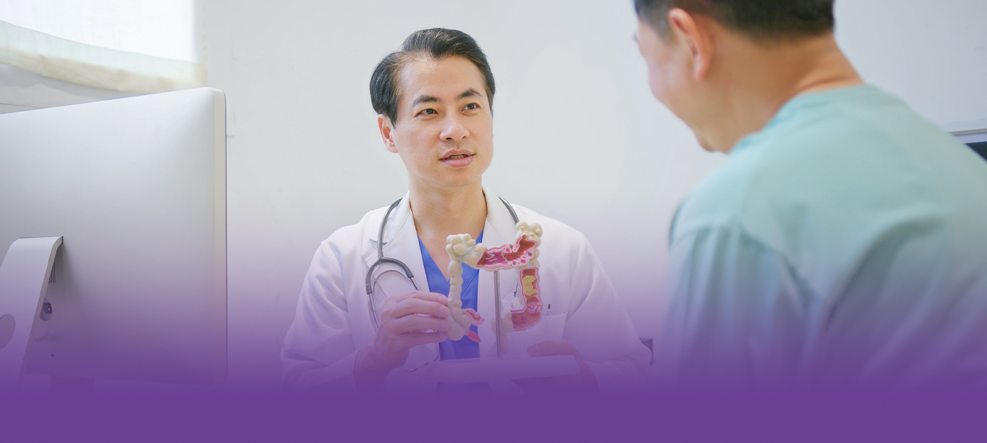 Arzt im Gespräch mit Patienten – zeigt ein Modell des Verdauungstraktes