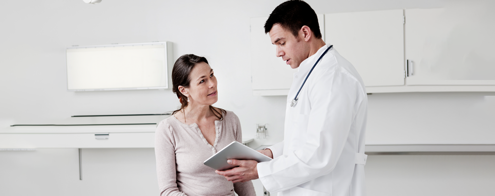Arzt zeigt Patientin eine DiGA auf dem Tablet